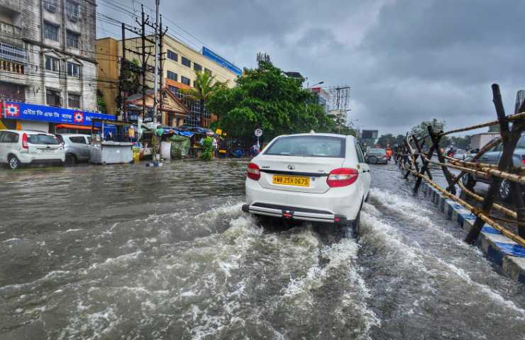 Un'auto sotto alla pioggia battente in città di pomeriggio