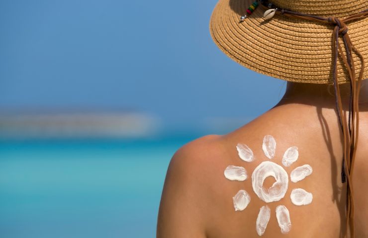 Una donna di spalle con il disegno di un Sole sulla sua pelle