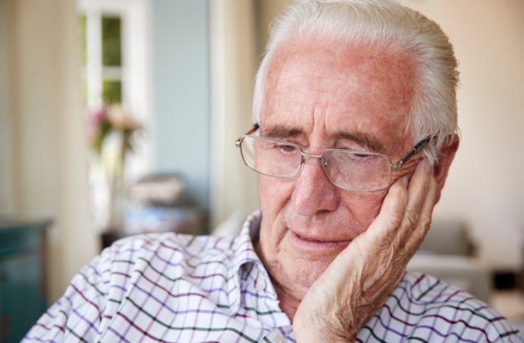 uomo anziano triste con una mano su una guancia