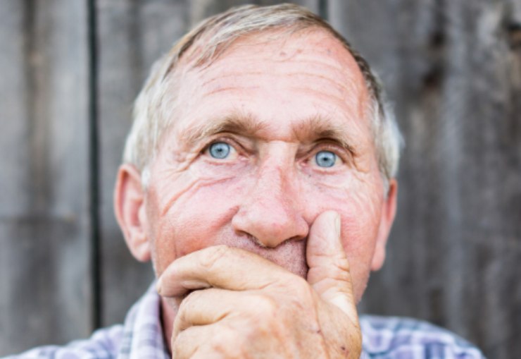 uomo anziano triste con una mano sulla bocca