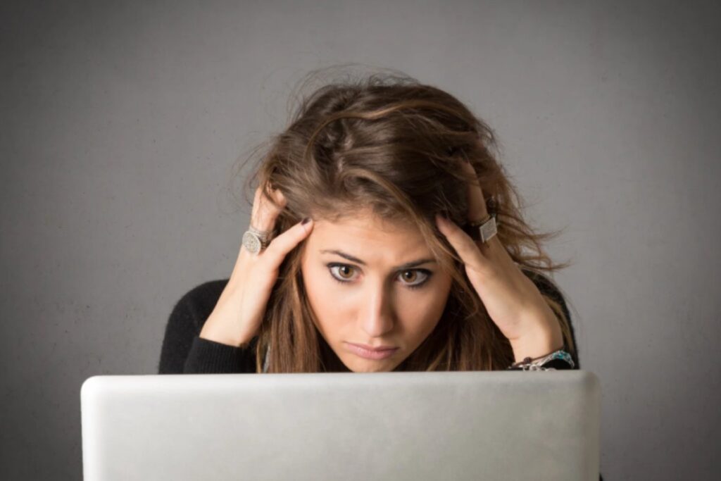 donna seduta davanti al computer con le mani nei capelli