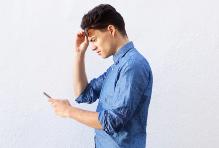 ragazzo che guarda il cellulare con aria perplessa