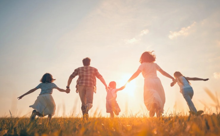 uomo e donna con 3 bambini che corrono su un prato
