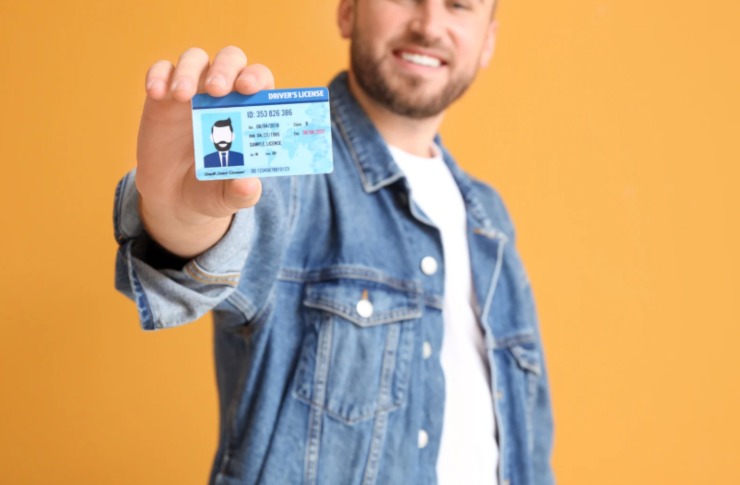 uomo che sorride con in mano la patente