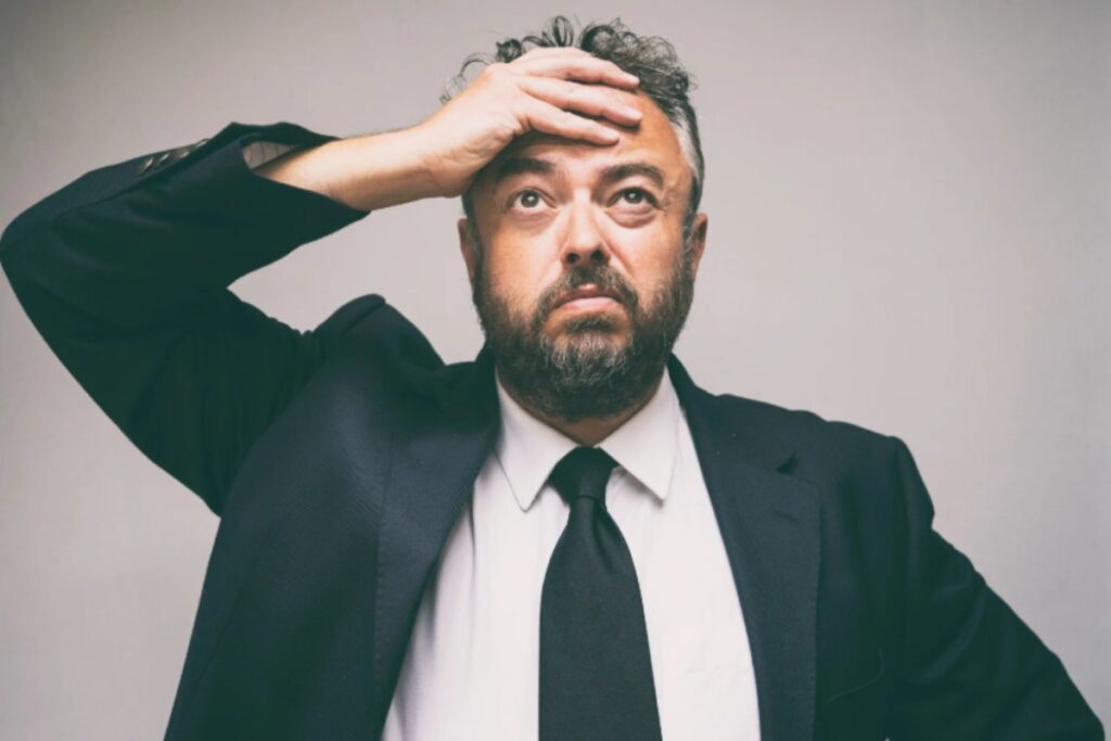 uomo preoccupato con una mano sulla fronte