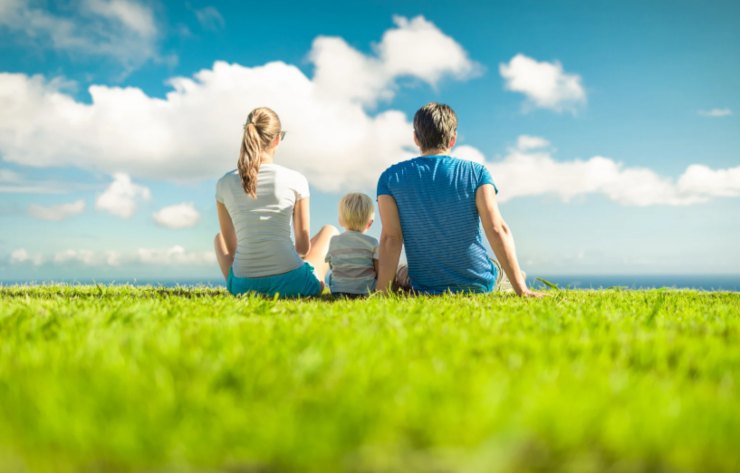mamma papà a bambino seduti su un prato