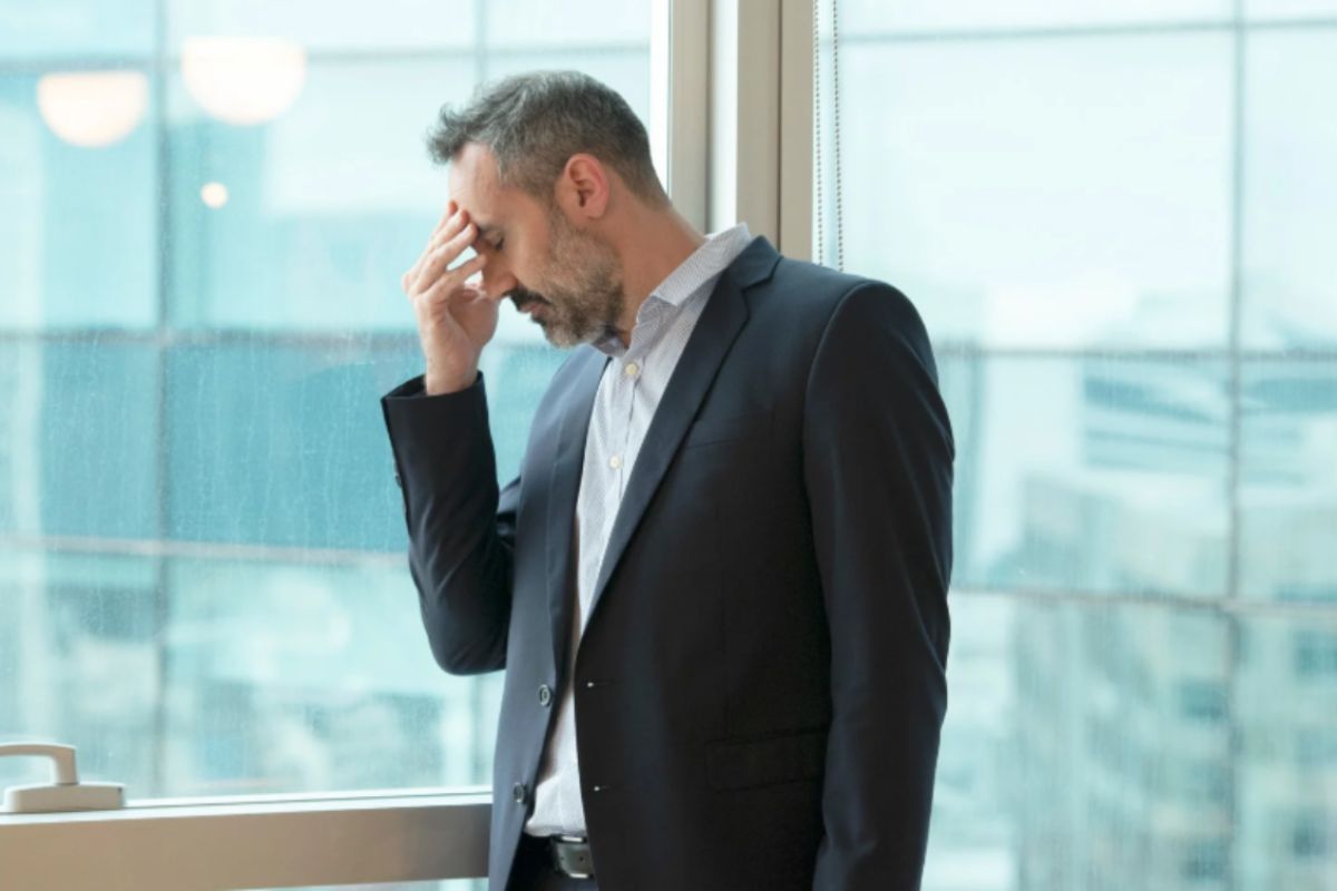uomo preoccupato con una mano sulla fronte