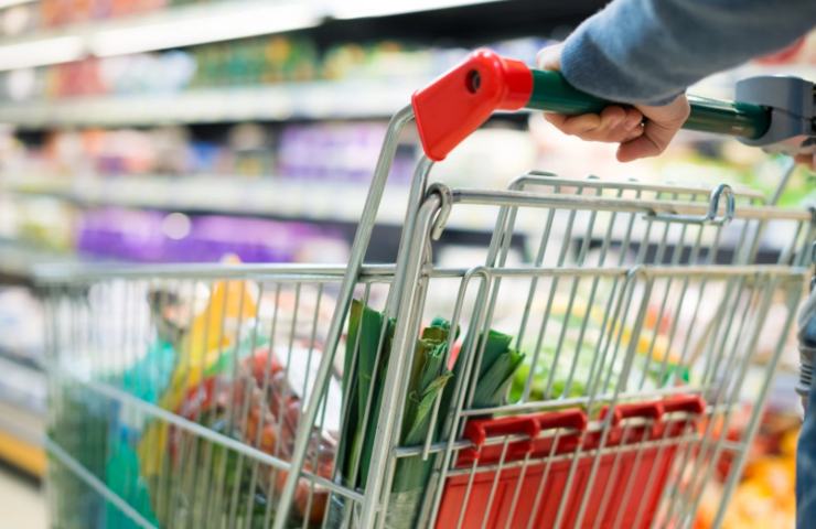 donna al supermercato che spinge il carrello della spesa