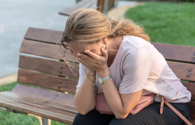 donna disperata seduta su una panchina con le mani in faccia