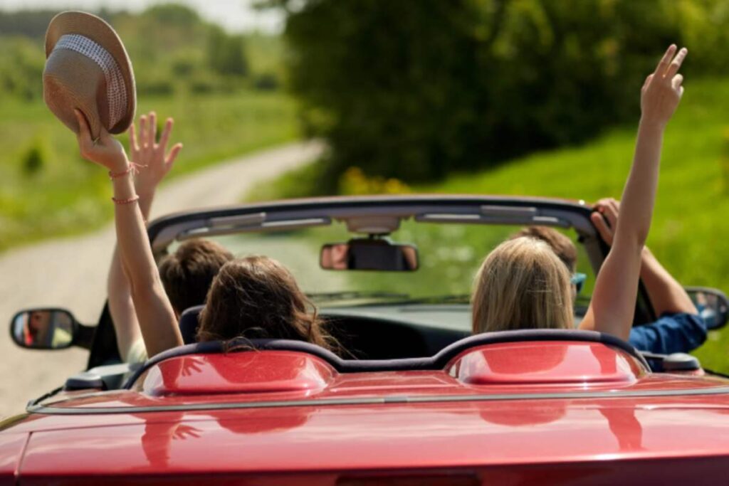 amici che viaggiano a bordo di un'auto rossa decappottabile