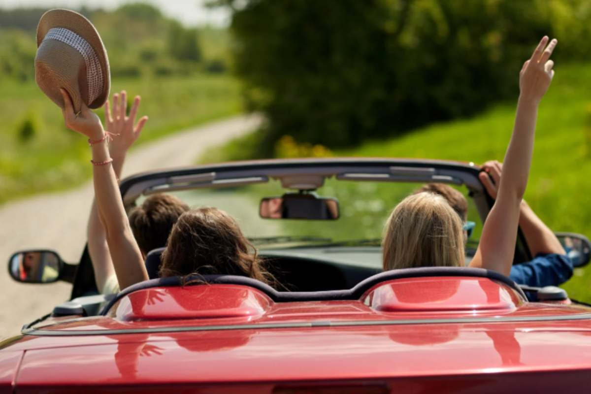amici che viaggiano a bordo di un'auto rossa decappottabile