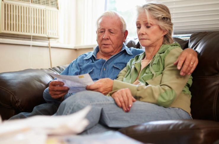 uomo e donna tristi seduti sul divano che leggono un foglio