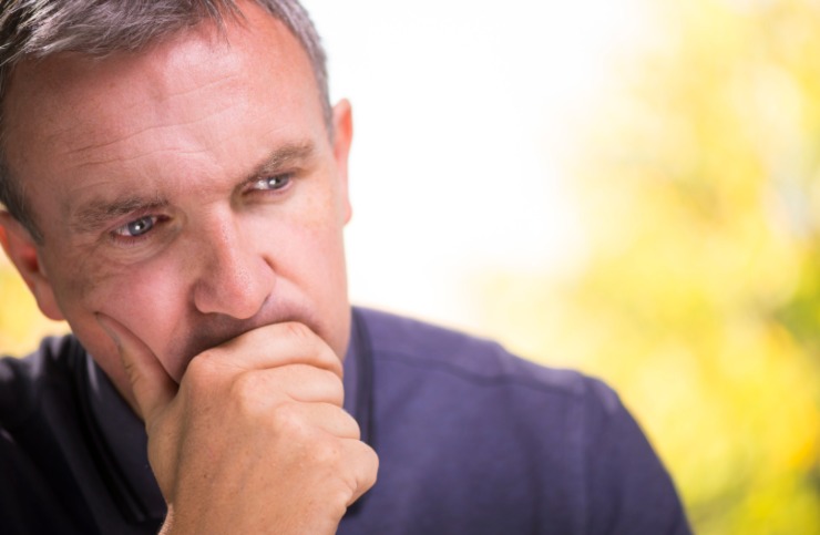 uomo pensieroso con una mano davanti alla bocca