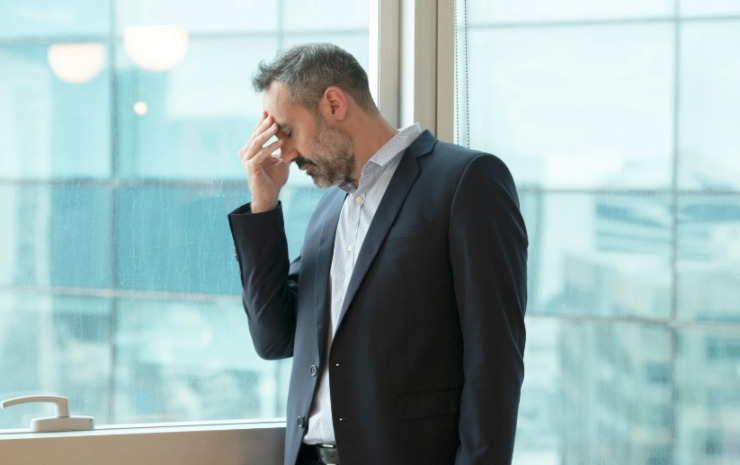 uomo preoccupato con una mano sulla fronte