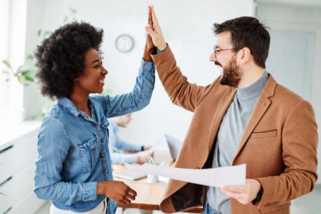 uomo e donna in ufficio che sorridono e battono il 5 con la mano