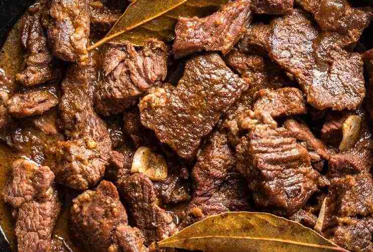 pezzi di carne cotta fumante e foglie di alloro