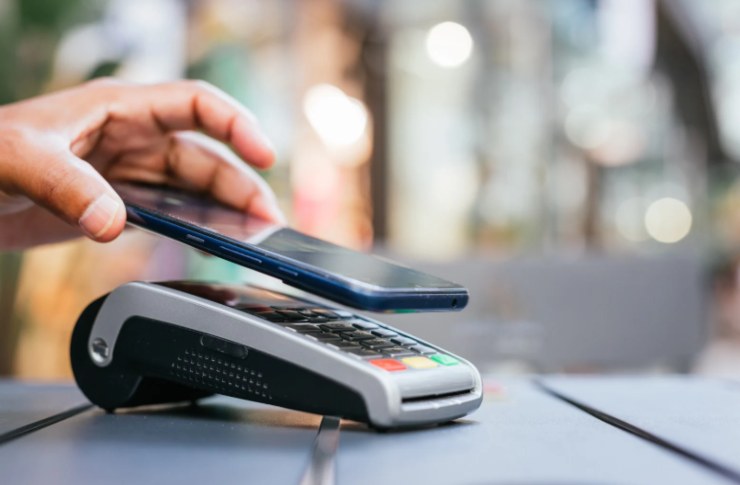 persona che avvicina il cellulare al pos per pagare