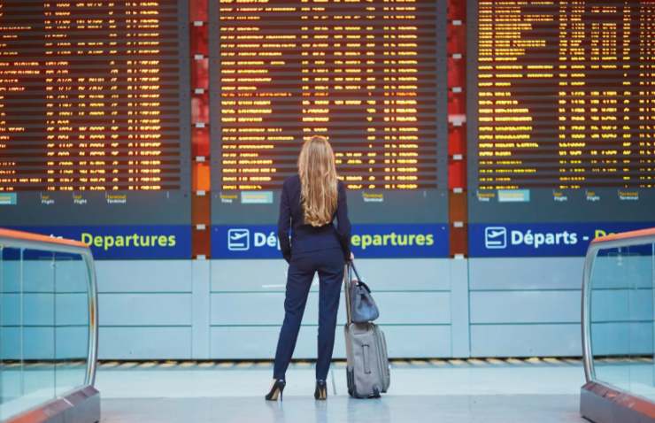 donna in aeroporto che controlla gli orari sul tabellone