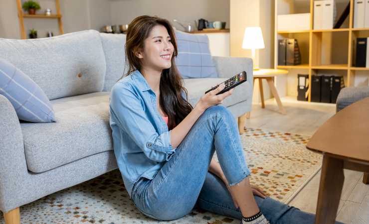 donna con telecomando seduta su tappeto