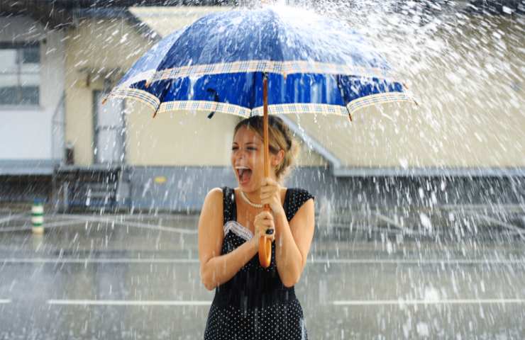 Una donna con l'ombrello sotto alla pioggia