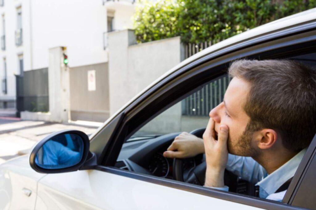 uomo in auto preoccupato che guarda fuori dal finestrino