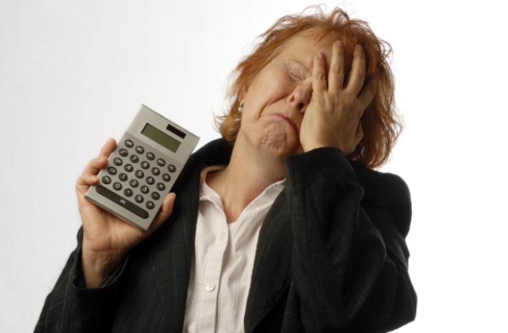 donna disperata con una mano in faccia e una calcolatrice nell'altra mano