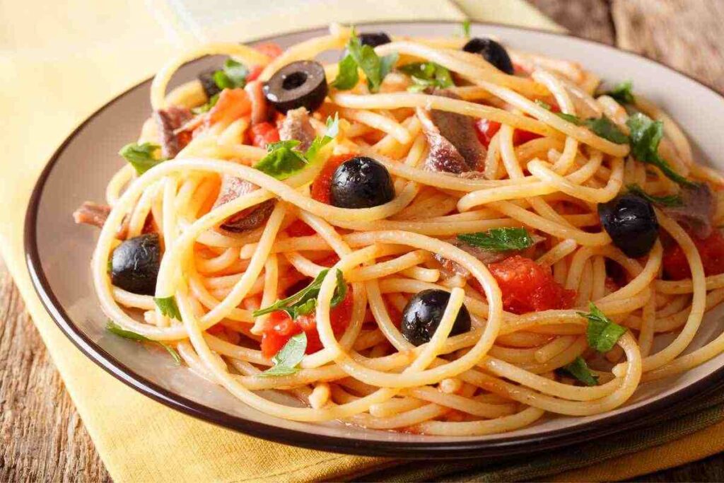 piatto di spaghetti con pomodorini, acciughe e olive nere