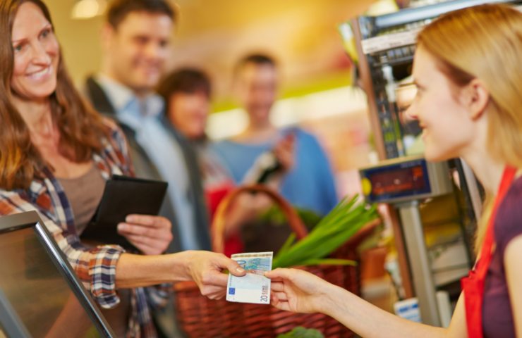 donna che sorride mentre paga alla cassa del supermercato 