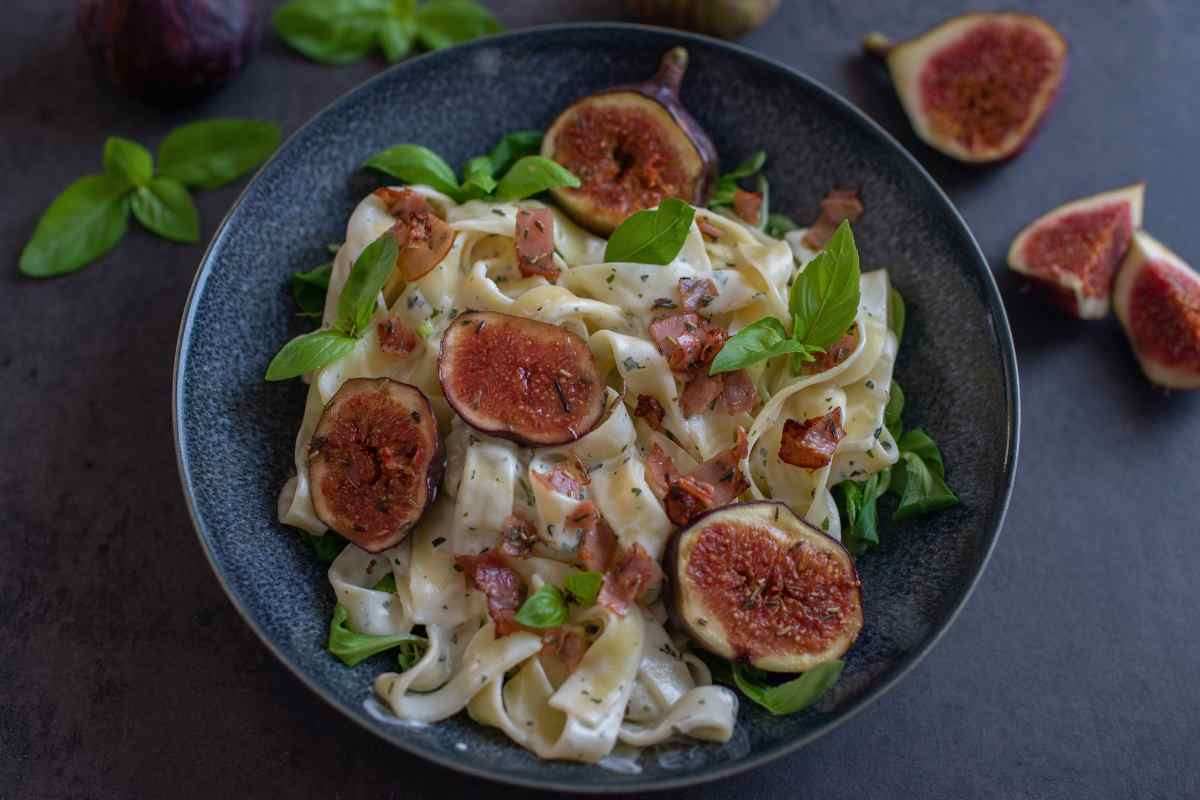 piatto di tagliatelle con fichi, pancetta, panna e basilico