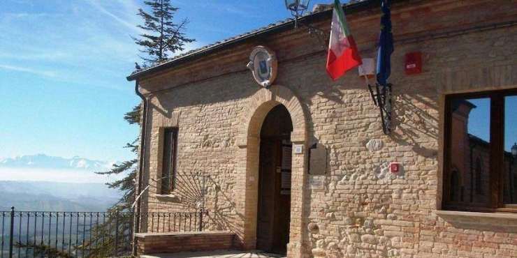 palazzo in pietra con bandiere e panorama alle spalle