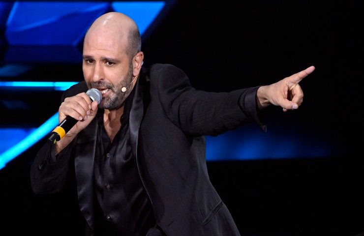 Checco Zalone con un microfono in mano
