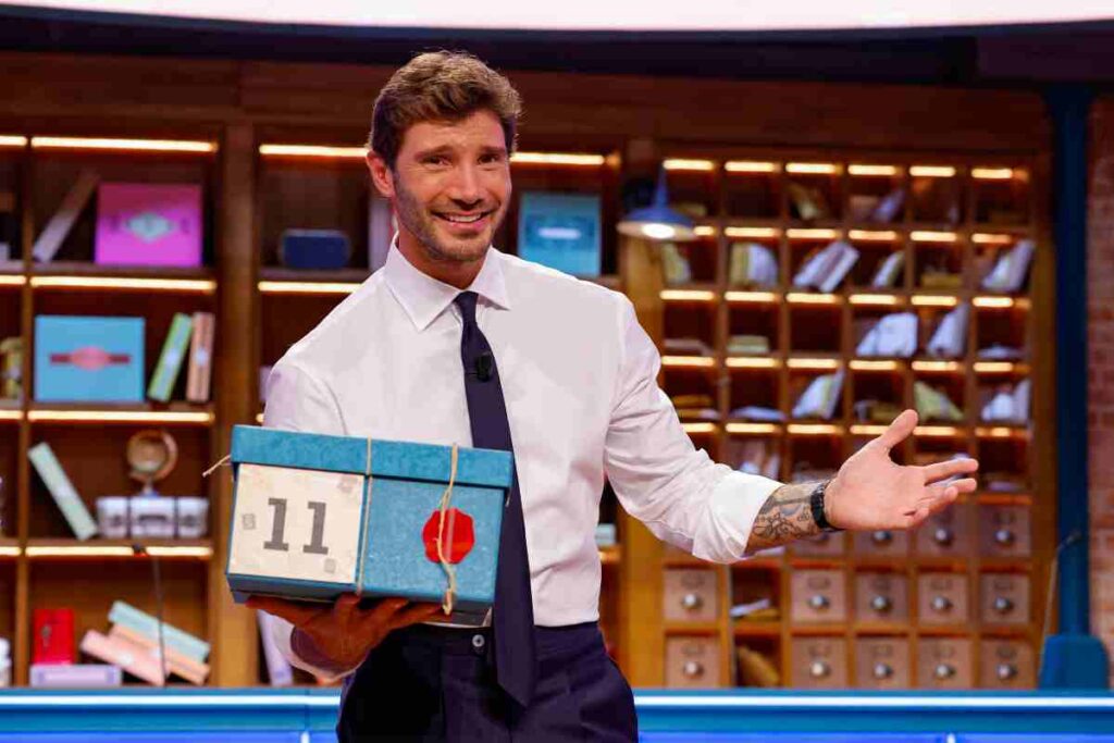 Stefano De Martino sorride con un pacco di Affari Tuoi