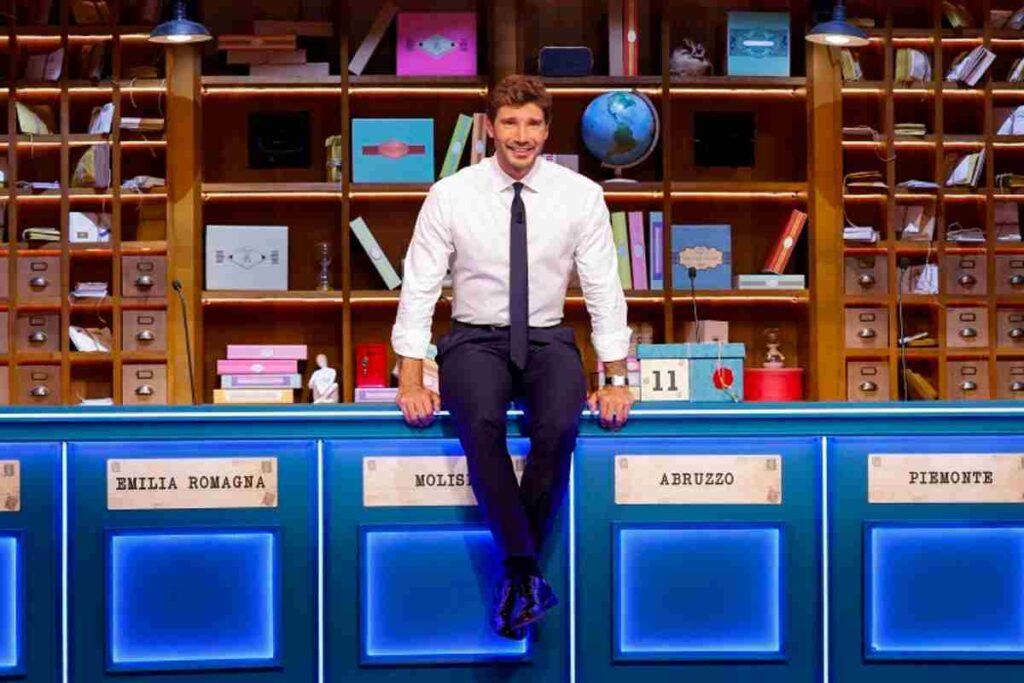 Stefano De Martino seduto sui banconi di Affari Tuoi