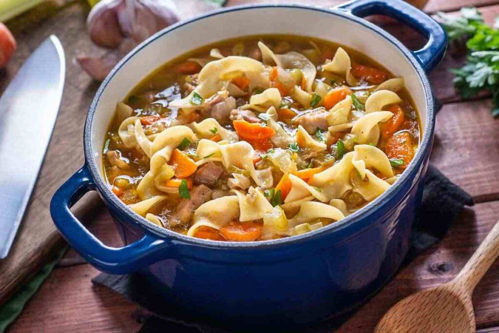 pentola con minestra di pasta, verdure, carne e legumi