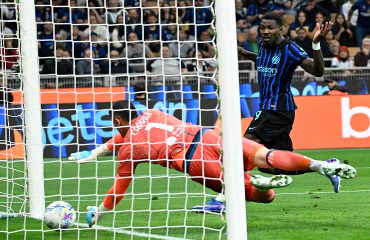Marcos Thuram manda il pallone oltre la linea con Elia Caprile del Cagliari che si tuffa invano, scena vista da un lato della porta.