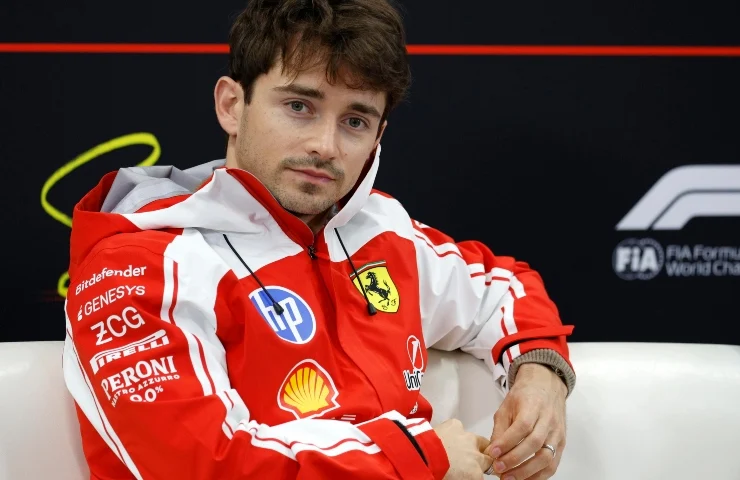 Charles Leclerc in tuta Ferrari in un momento di pausa ai box.