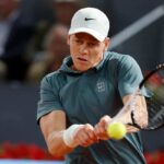 Jannik Sinner colpisce la pallina con la racchetta esibendosi in un rovescio a due mani.