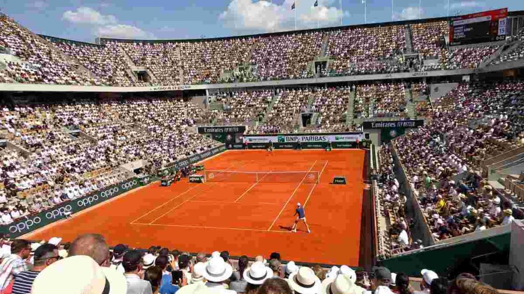 Tifosi sugli spalti del Roland Garros 2026 durante una partita di Jannik Sinner sulla terra rossa di Parigi in una giornata soleggiata.