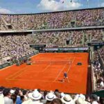 Tifosi sugli spalti del Roland Garros 2026 durante una partita di Jannik Sinner sulla terra rossa di Parigi in una giornata soleggiata.