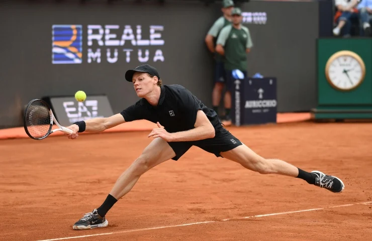 Jannik Sinner si allunga per colpire la pallina con la racchetta tenuta nella mano destra.