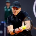 Jannik Sinner colpisce di rovescio in doppie mani la palla di tennis con la racchetta.