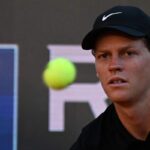 Jannik Sinner concentrato nel colpire la palla che viaggia verso lui.