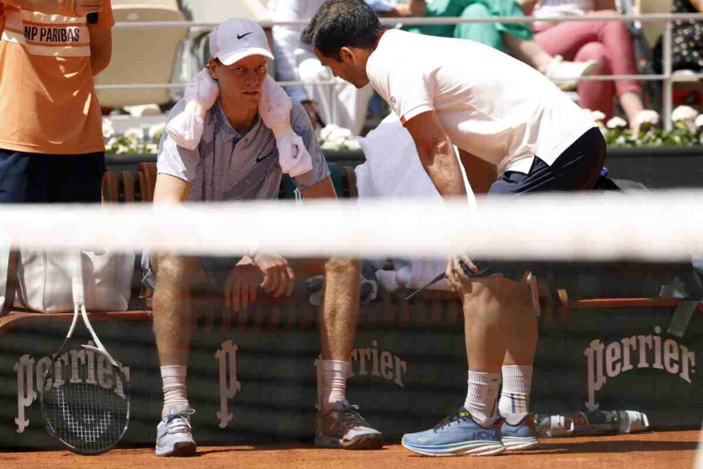 Jannik Sinner seduto a bordo campo colpito da un malessere.