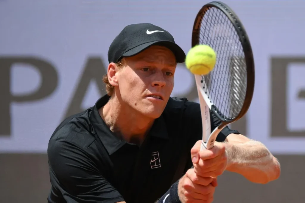 Jannik Sinner colpisce la pallina alla racchetta usando entrambe le mani.