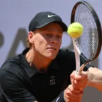 Jannik Sinner colpisce la pallina alla racchetta usando entrambe le mani.