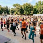 Grande gruppo di persone che fa fitness all'aperto a Roma per la Giornata Nazionale dello Sport, evento di ginnastica e corsa in un parco italiano.