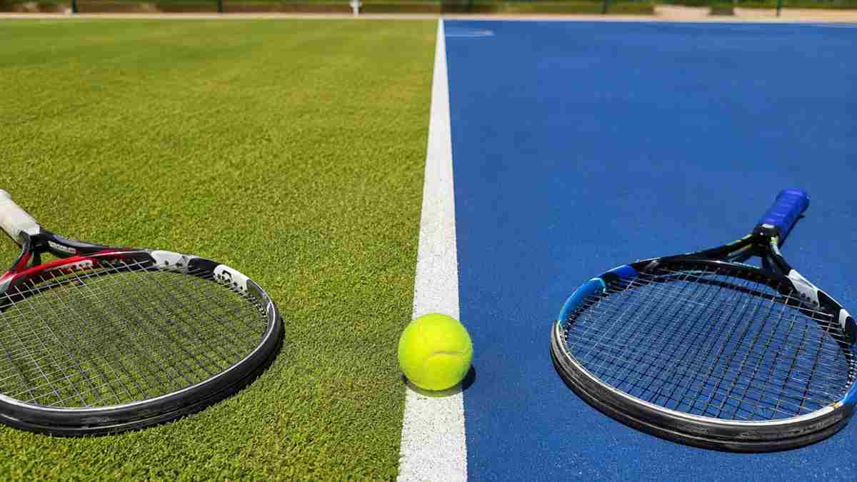 Campo da tennis diviso tra erba e cemento con pallina e racchette, simbolo del passaggio di superficie nel tennis professionistico.