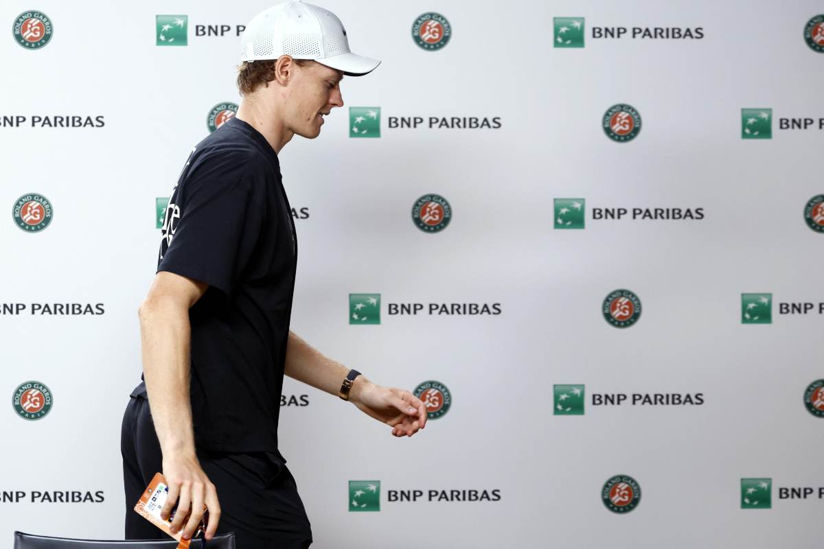 Jannik Sinner inquadrato di profilo davanti al cartonato degli sponsor.