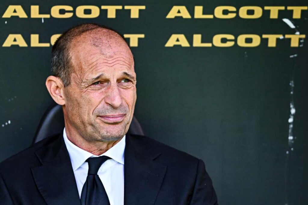 Massimiliano Allegri in tenuta formale seduto in panchina guarda fuori dall'obiettivo.