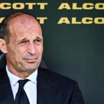 Massimiliano Allegri in tenuta formale seduto in panchina guarda fuori dall'obiettivo.